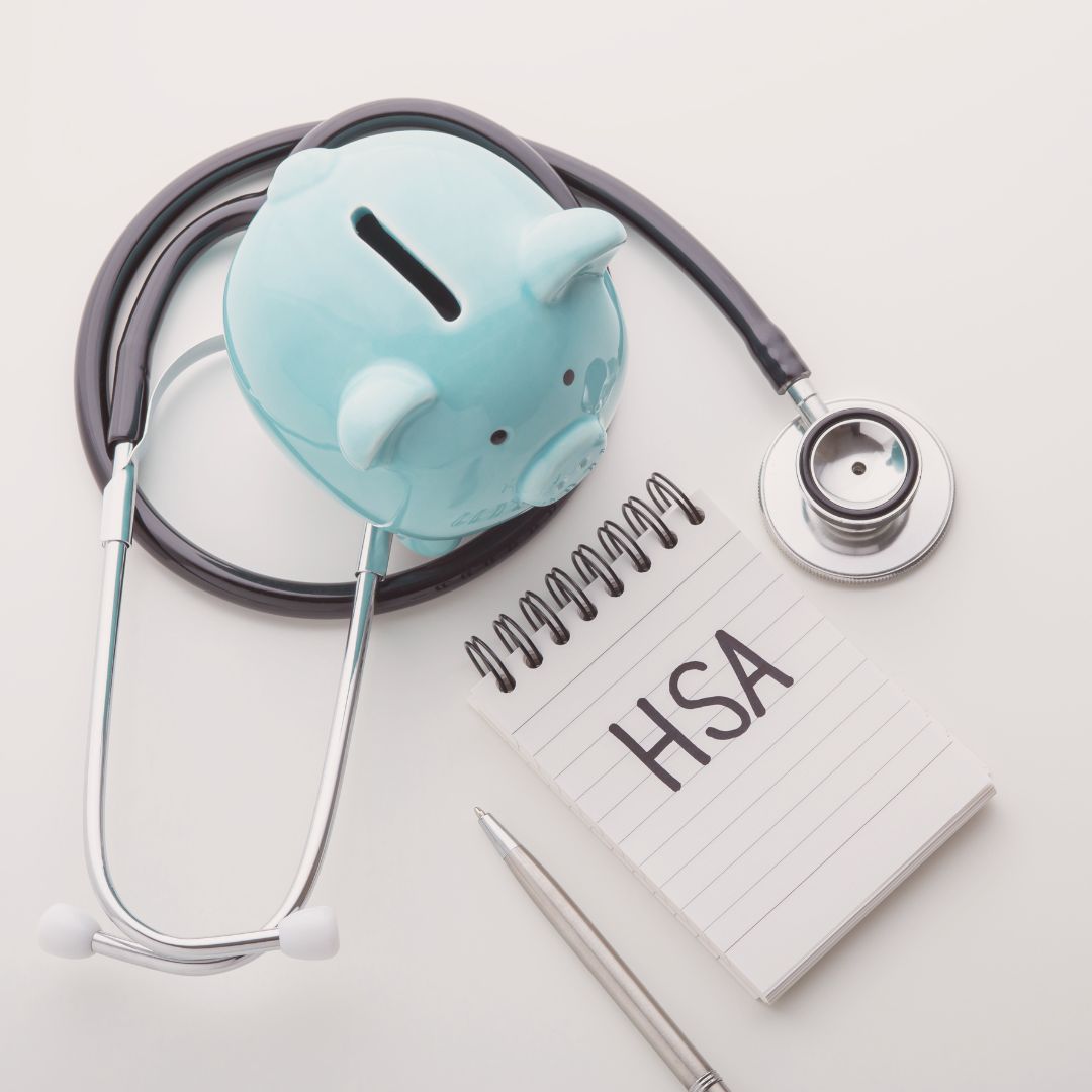 a blue piggy bank and a stethoscope with a pad saying HSA for health savings account. you can buy compression gloves or arthritis gloves using hsa or fsa accounts or cards at graceandable.com