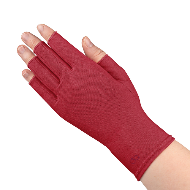 A close up of the hand of a woman with arthritis, wearing Chili Red Compression Gloves and showing the back of her hand.