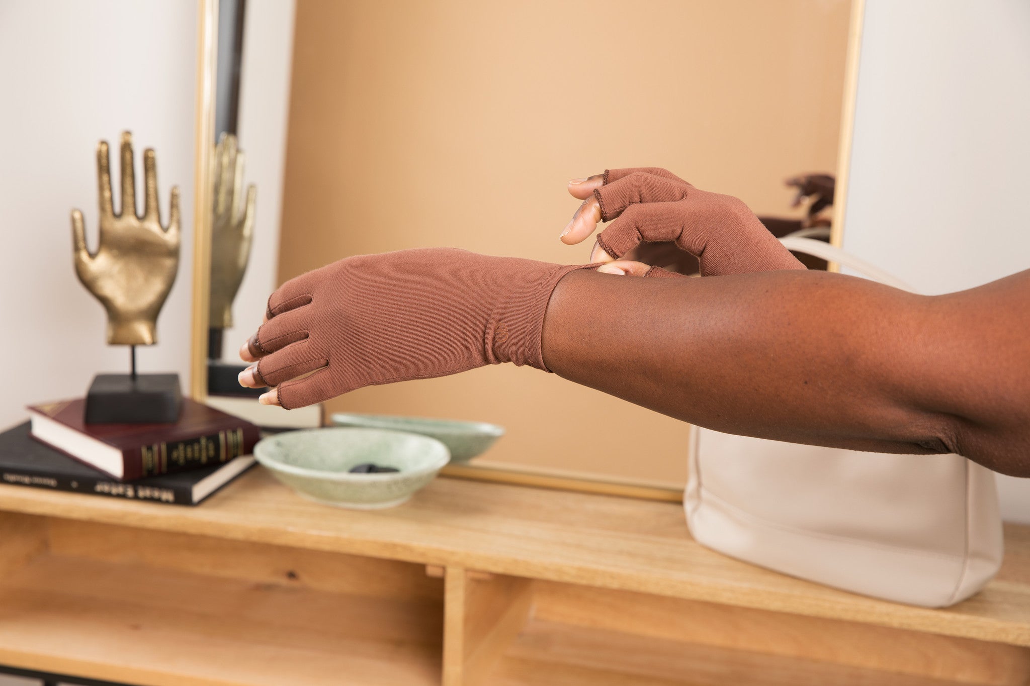 Cocoa Brown Compression Gloves on a woman's hand slightly stretching the end of one glove